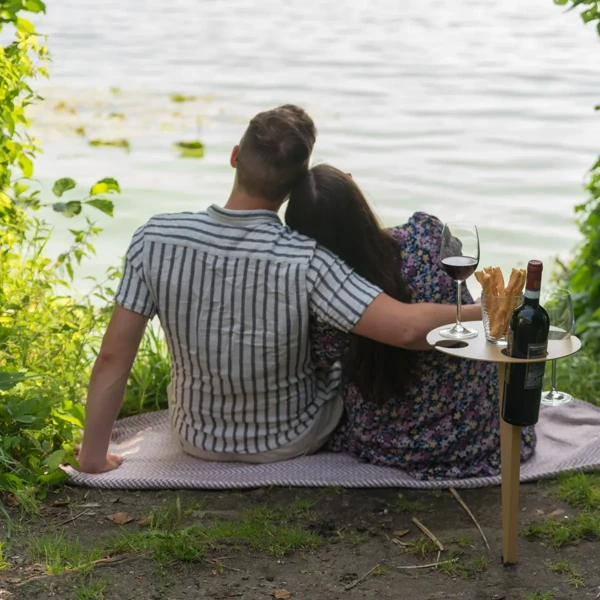 Paar am Seeufer mit Porto Vino Weintisch in Bronze, Weinflasche und zwei Gläsern