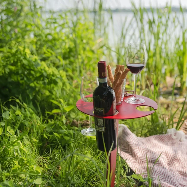 Detailaufnahme des roten Porto Vino Weintisches am Seeufer mit Weinflasche, Gläsern und Grissini